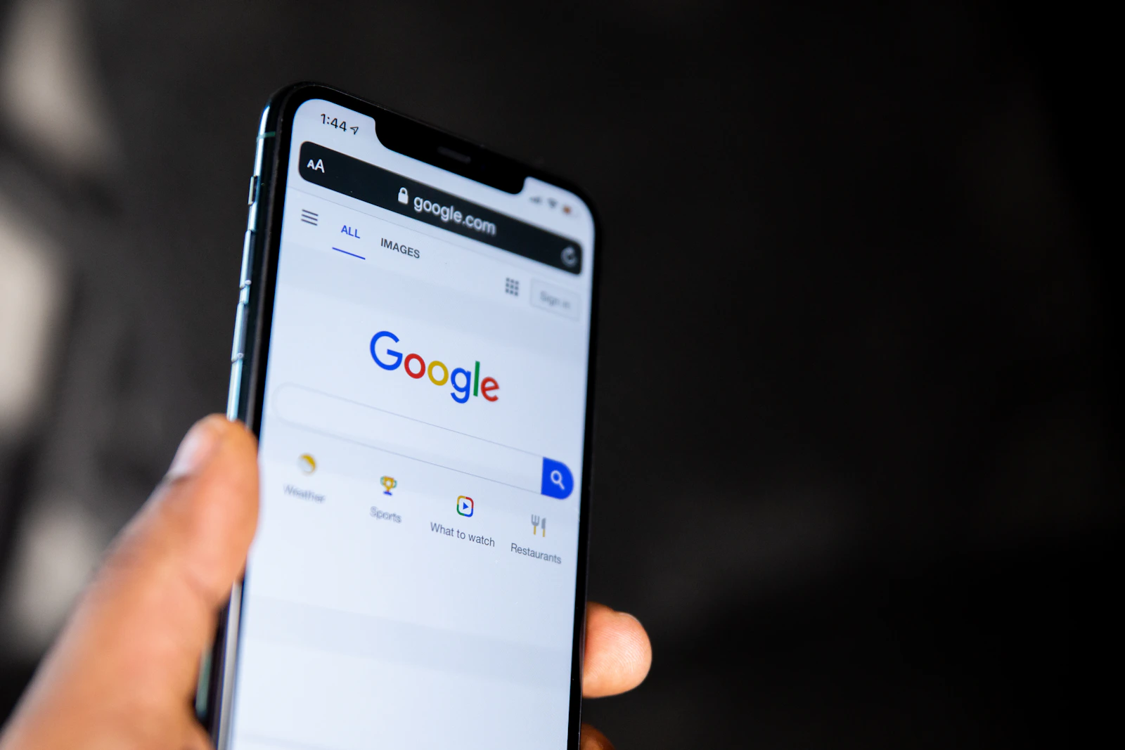 Smartphone affichant la page d'accueil du moteur de recherche Google tenu dans une main