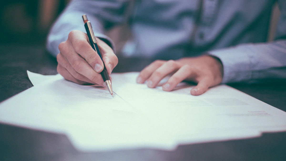 Personne signant un document avec un stylo sur un bureau
