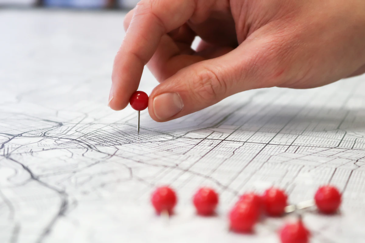 Main plaçant une épingle rouge sur un plan de ville, symbole de position dans le pack local Google Maps